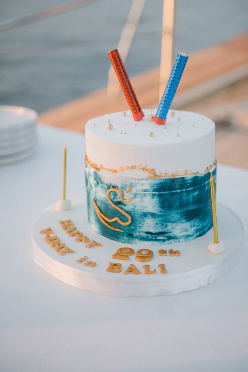 Ombre cake with gold Shivanna swan reading "Happy V-Day 29th in Bali" on a yacht table
