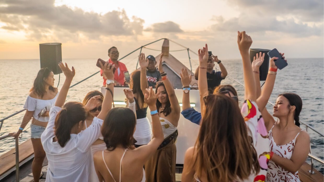 Guests dancing with the DJ on deck during a sunset cruise