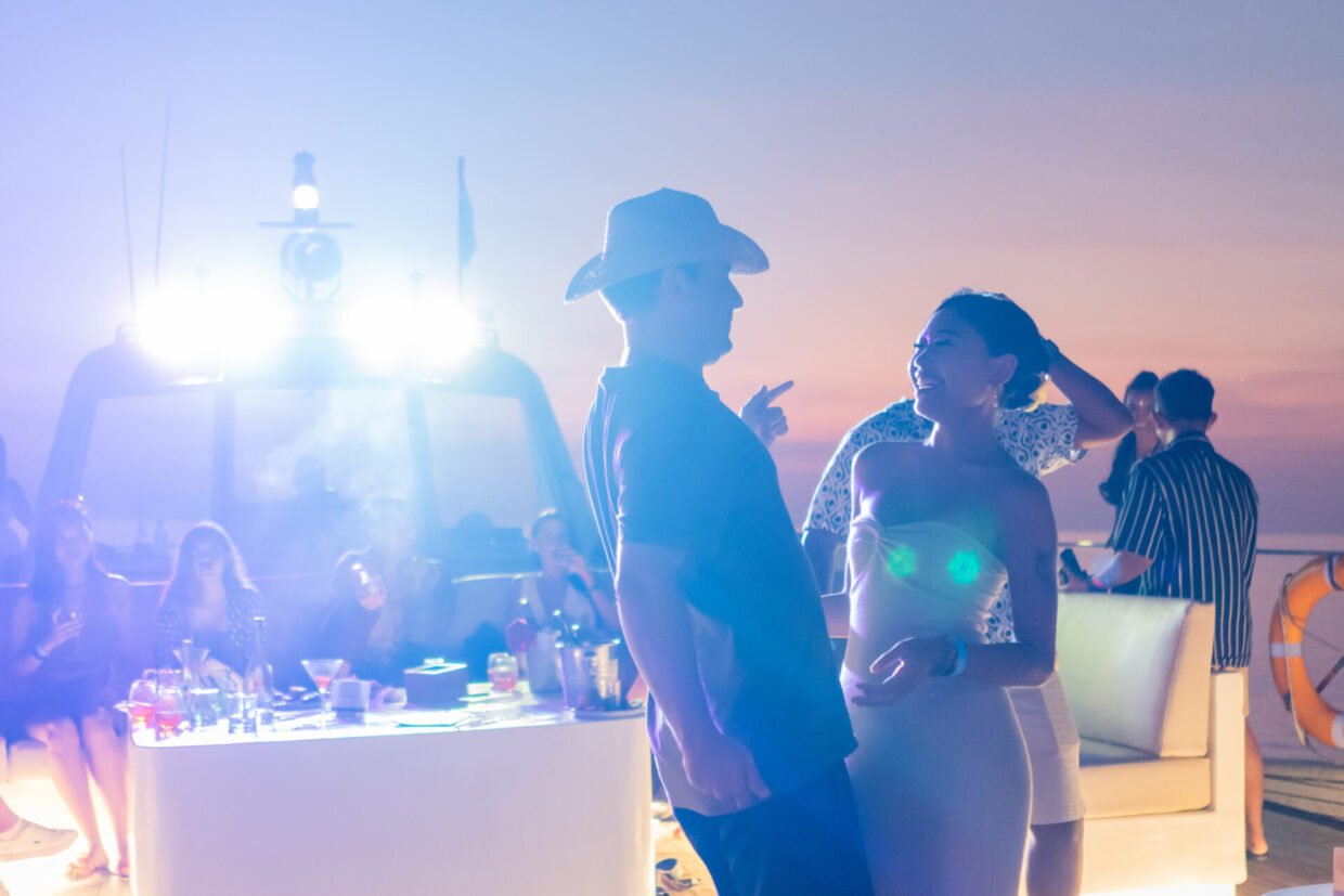 Guests mingling at the deck bar under stage lights at dusk