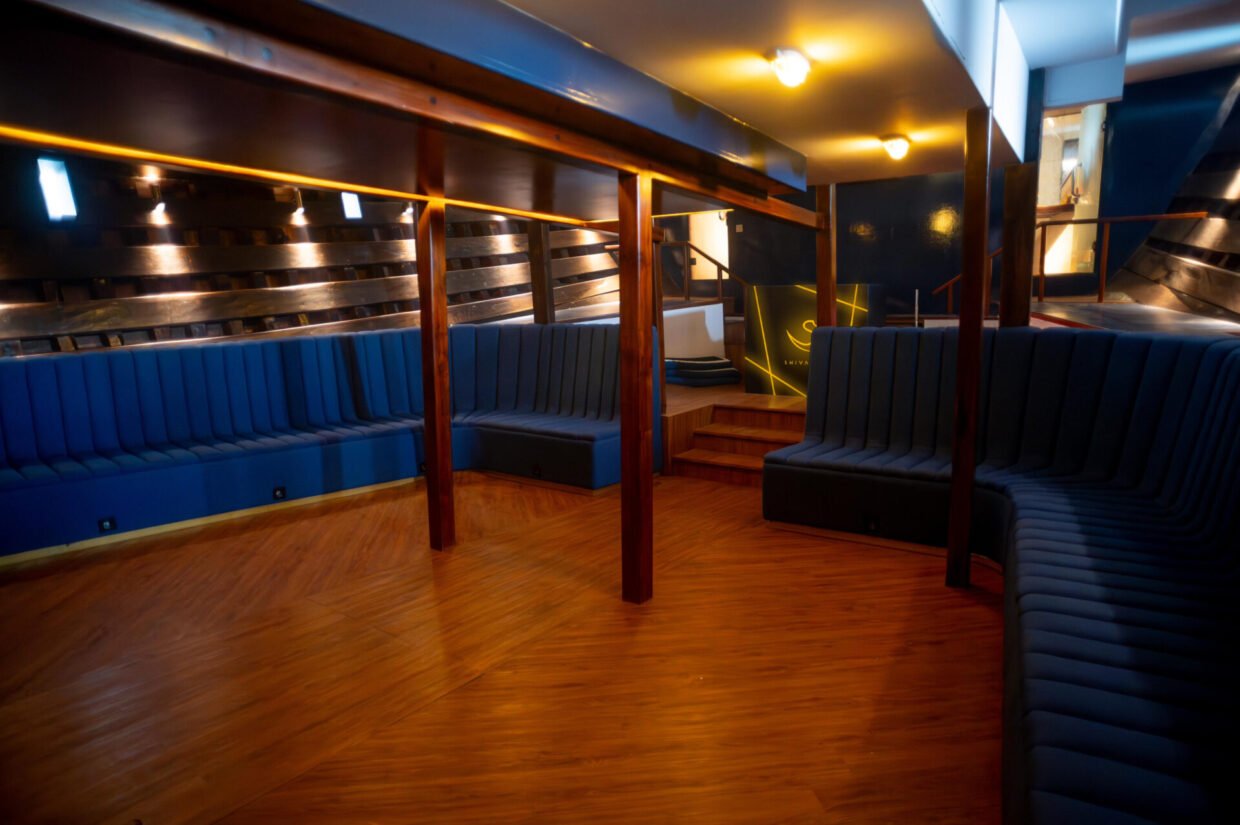 Lower deck saloon with blue upholstered booths, timber floors and warm strip lighting