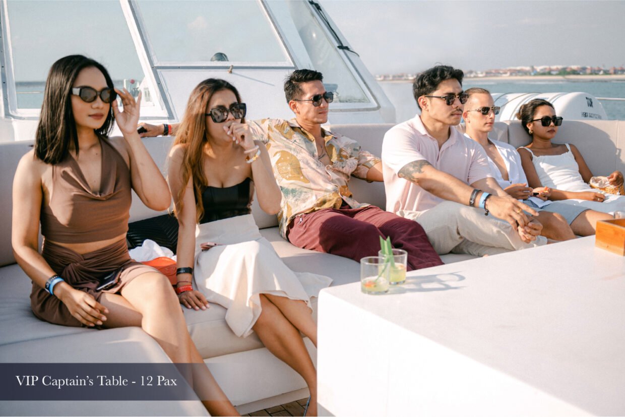 Guests in sunglasses relaxing at the VIP Captain's Table lounge on deck