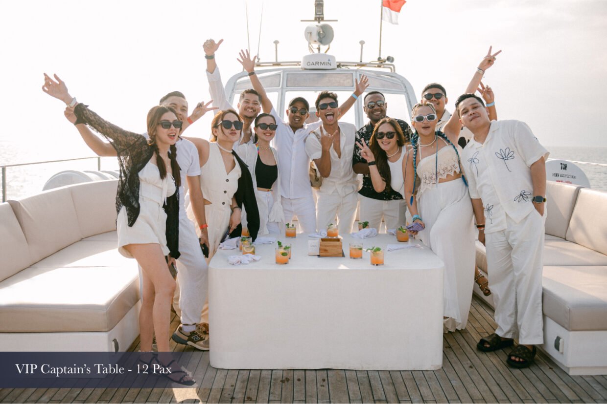Group in white celebrating with cocktails at the VIP Captain's Table on deck