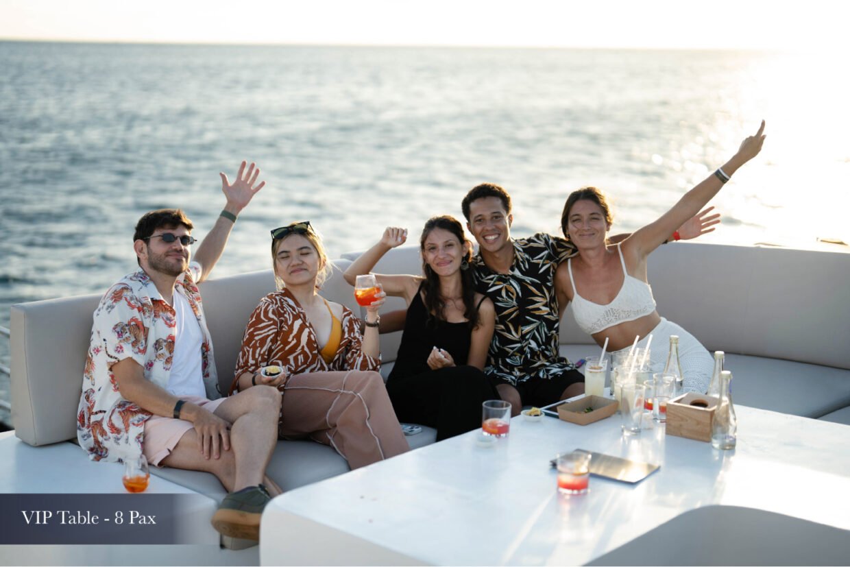 Five guests toasting cocktails on a VIP deck sofa during the sunset cruise