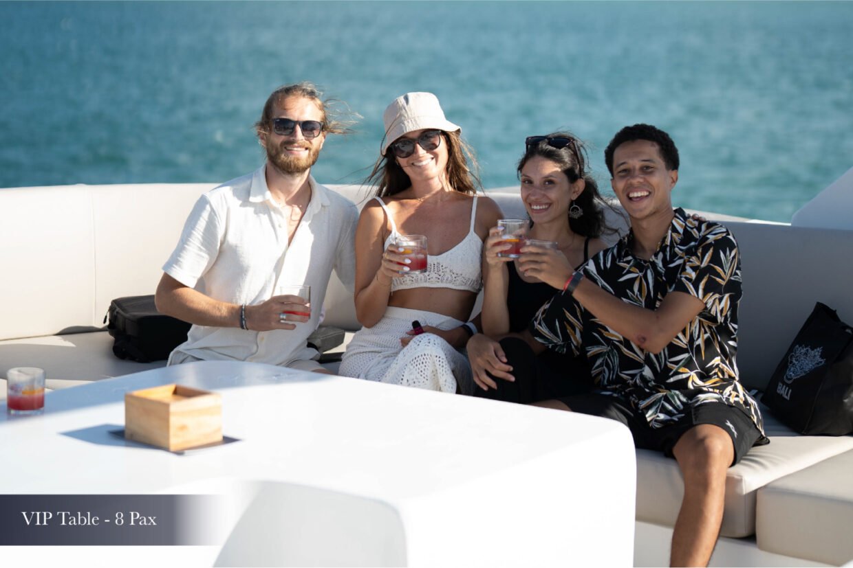 Four guests with cocktails on a sunlit VIP deck sofa aboard the yacht