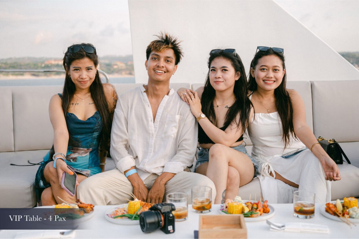 Four young guests seated at a VIP table laid with grilled food