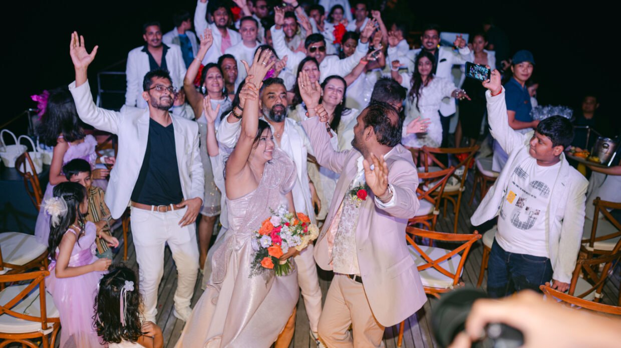Bride and groom celebrating with cheering guests at a yacht-deck wedding reception