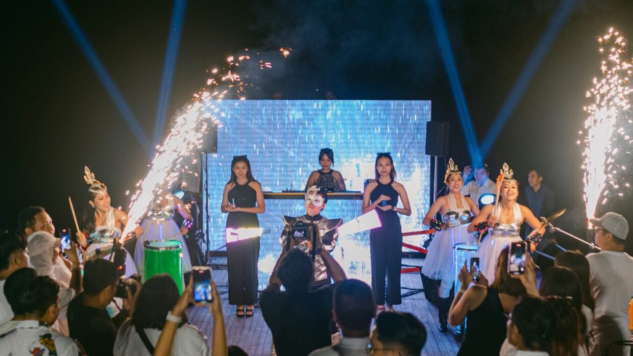 Dancers with sparklers perform before a crowd at a nighttime deck show