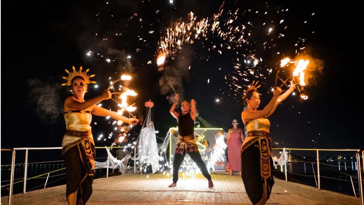Balinese fire dancers performing with flaming props on the yacht deck at night