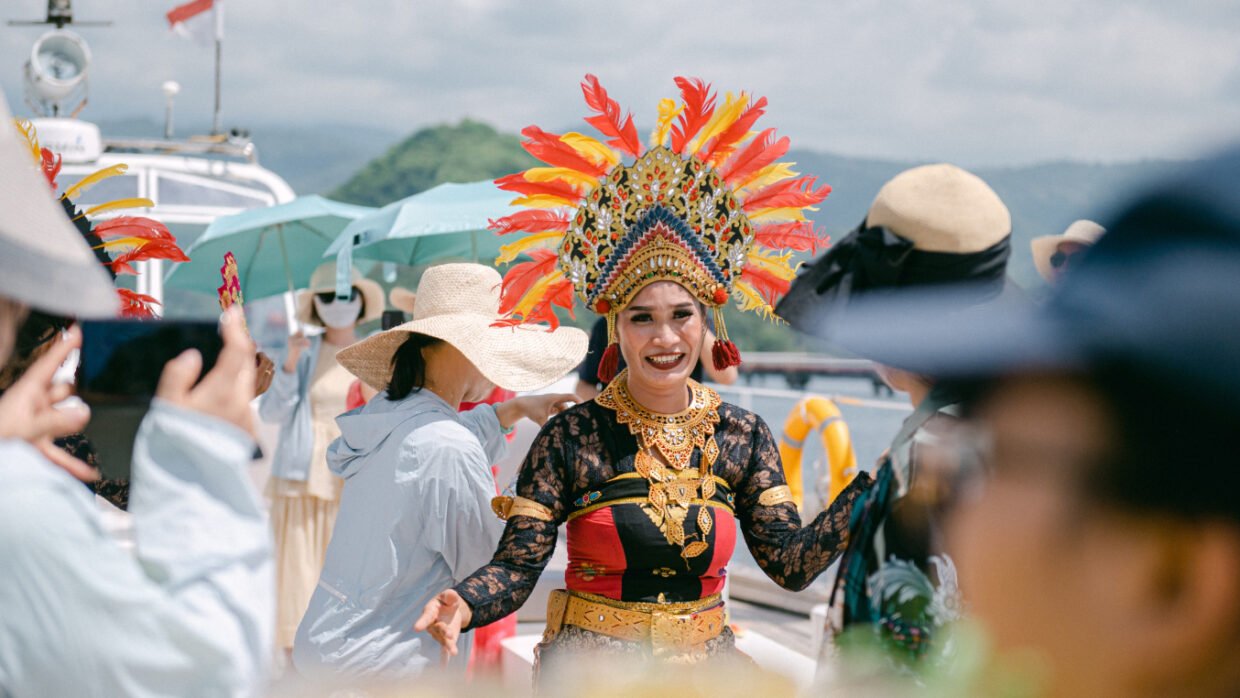 Smiling Balinese performer in a feathered headdress greets guests at the harbour