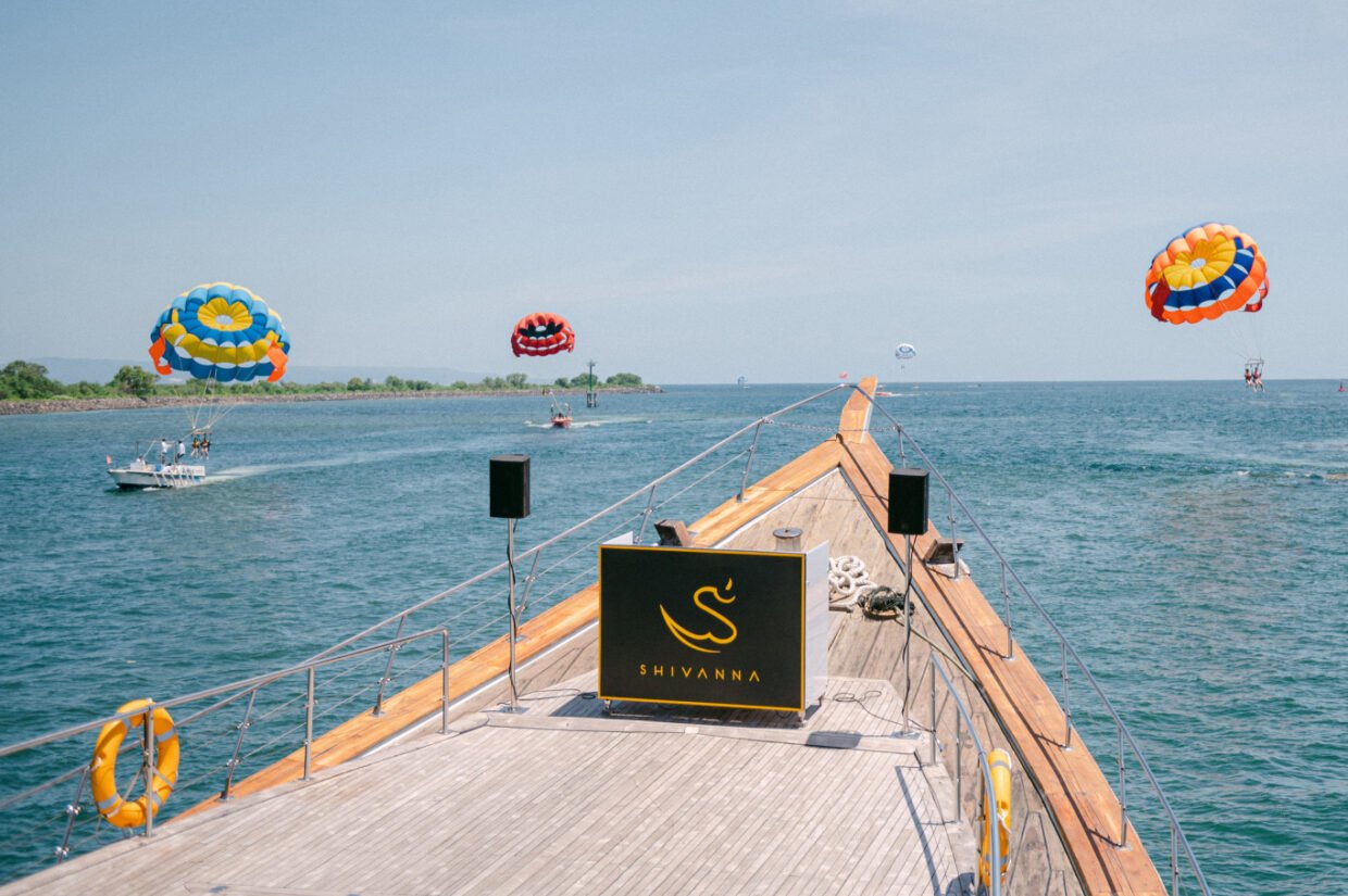Shivanna yacht bow signage overlooking parasailers above the Nusa Dua coastline