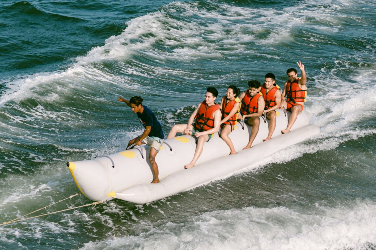 Group in life jackets riding a banana boat across the waves