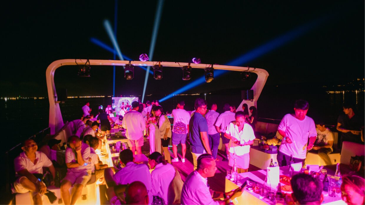 Guests mingling under blue stage lighting at a night party on deck