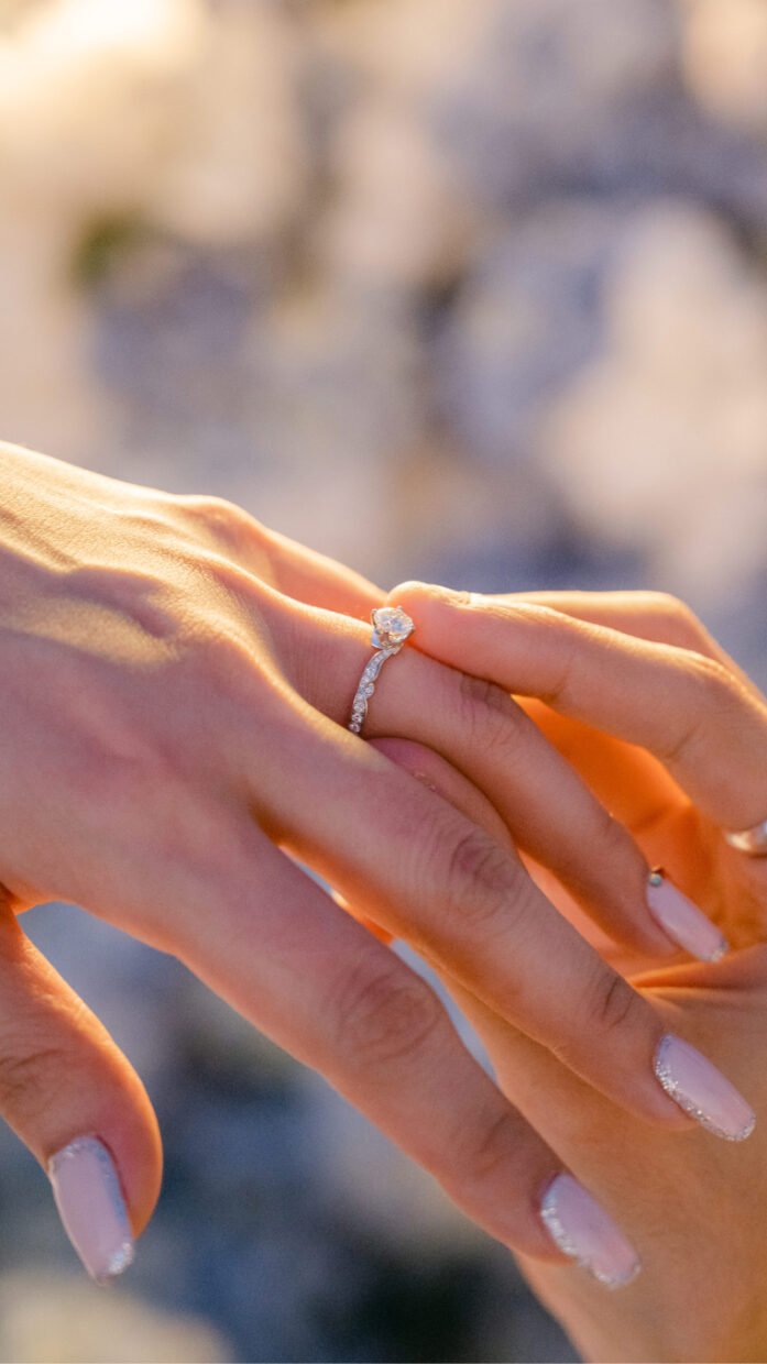 Close-up of a woman trying on a diamond engagement ring in warm sunset light