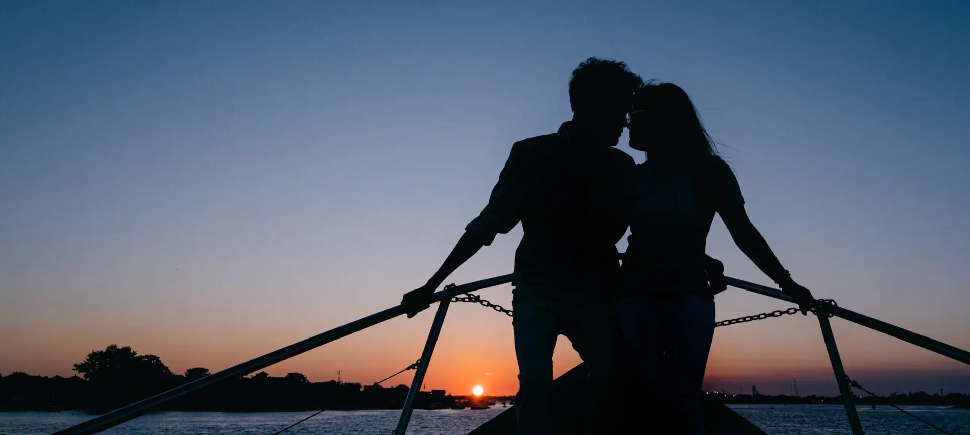 Couple silhouetted on the yacht bow against a Nusa Dua sunset