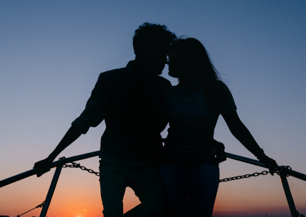 Silhouette of a couple embracing on the yacht bow at sunset