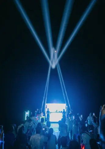 Crowd dancing under blue laser lights at a night yacht party