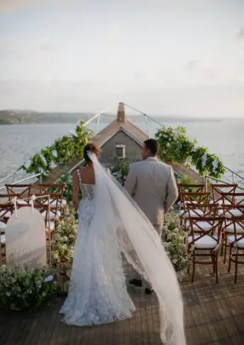 Bride and groom walking toward a floral arch wedding setup on the yacht deck