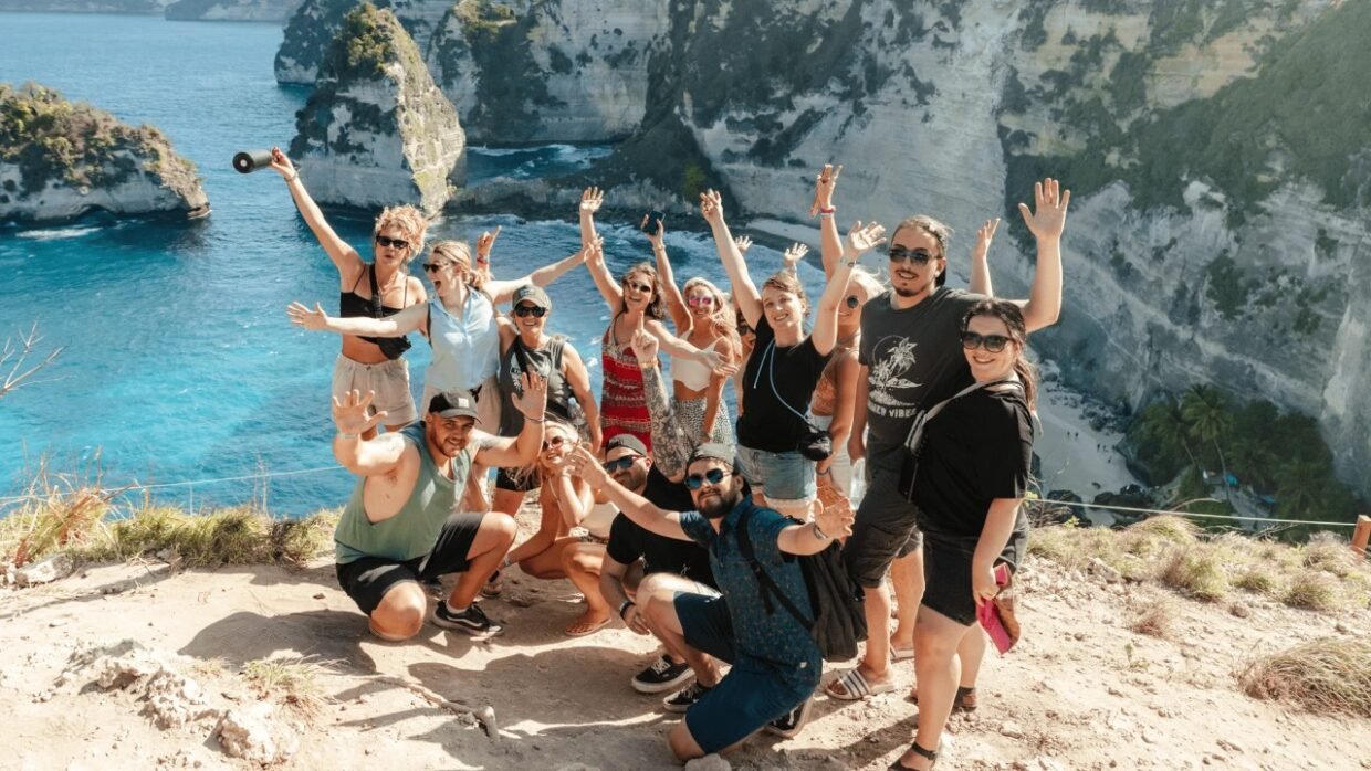 Group of travelers posing at a scenic cliff overlooking a turquoise beach.