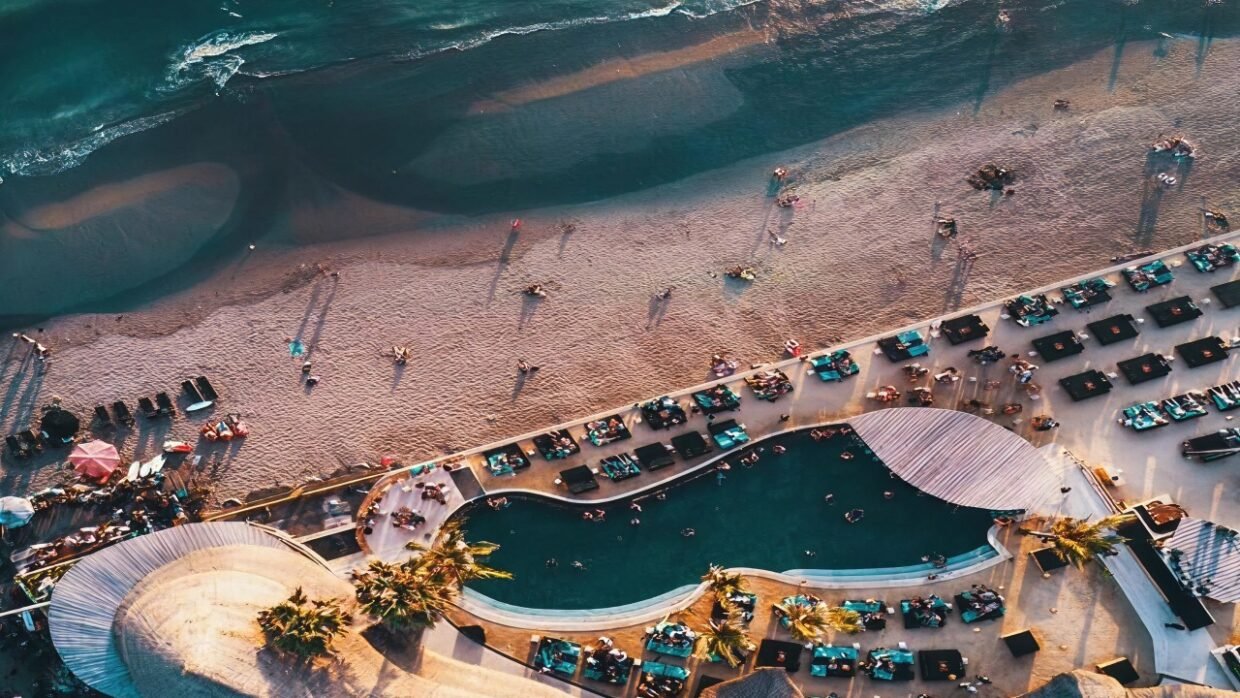 Aerial view of a beachfront pool overlooking the ocean at sunset.